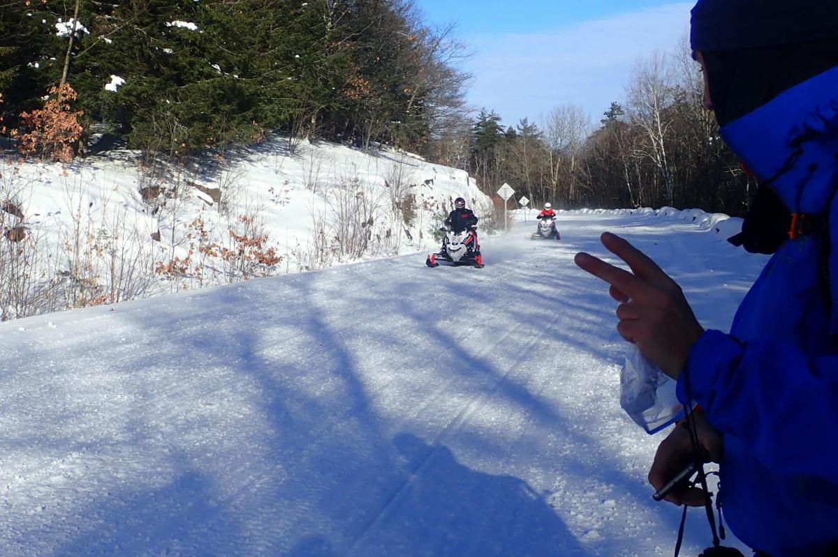 Snowmobilers on Prospect Mountain riding past a winter hiker