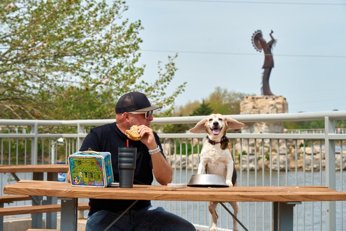 Darrin Hackney enjoys a picnic with his beagle with the Keeper of the Plains in the background