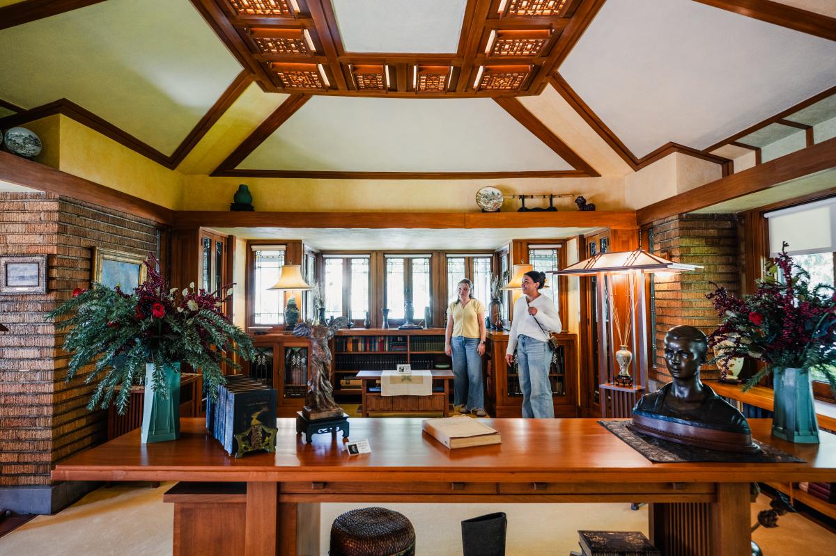 Two women tour the living room of the Frank Lloyd Wright Allen House