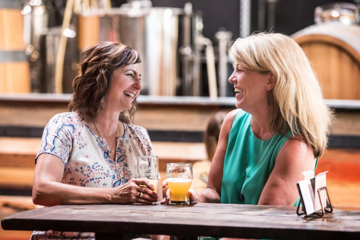Two women tell stories at a table while enjoying freshly brewed beers at Central Standard Brewing in Wichita, Kansas