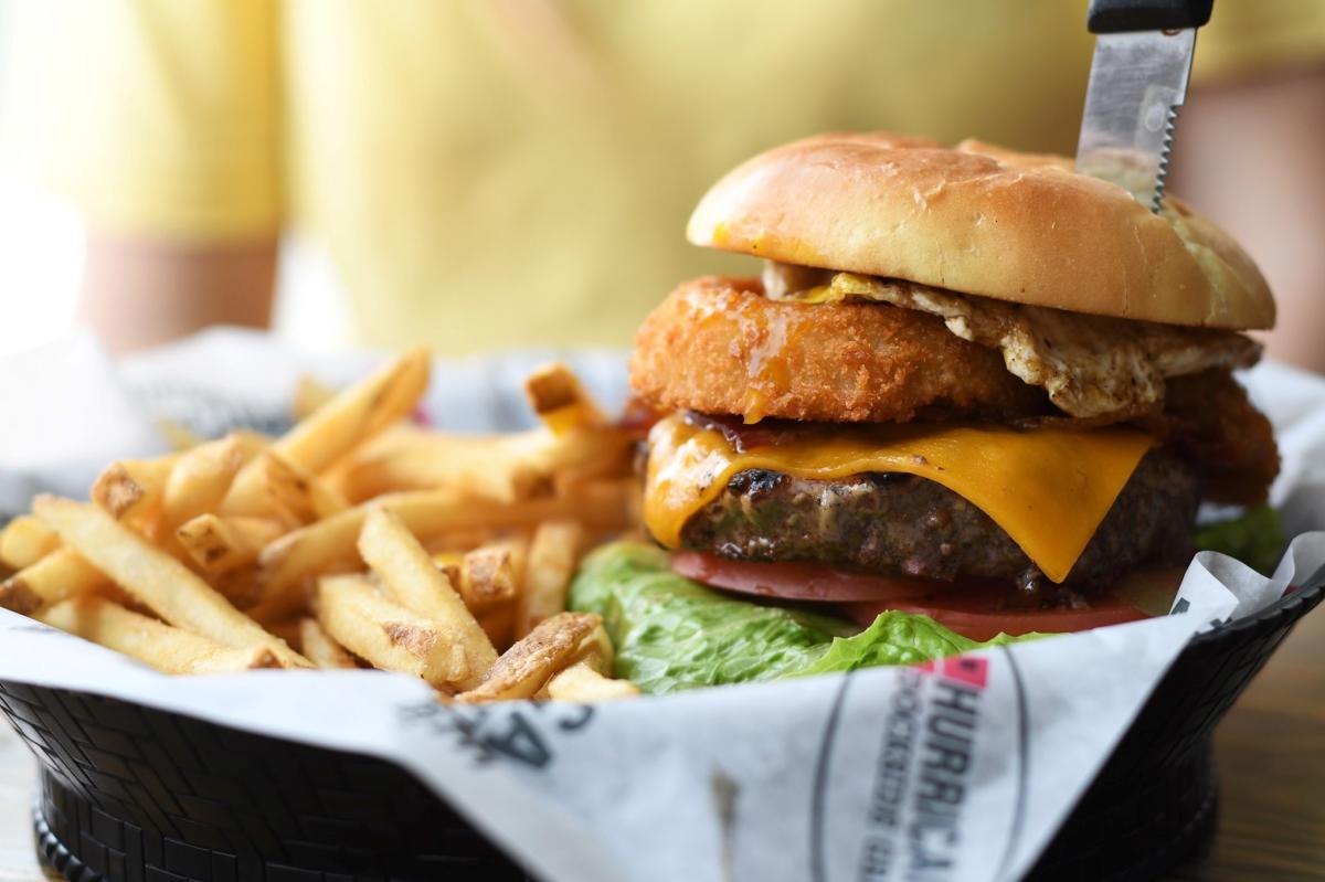 A burger is served topped with cheese and an onion ring at Hurricane Sports Gril in Wichita