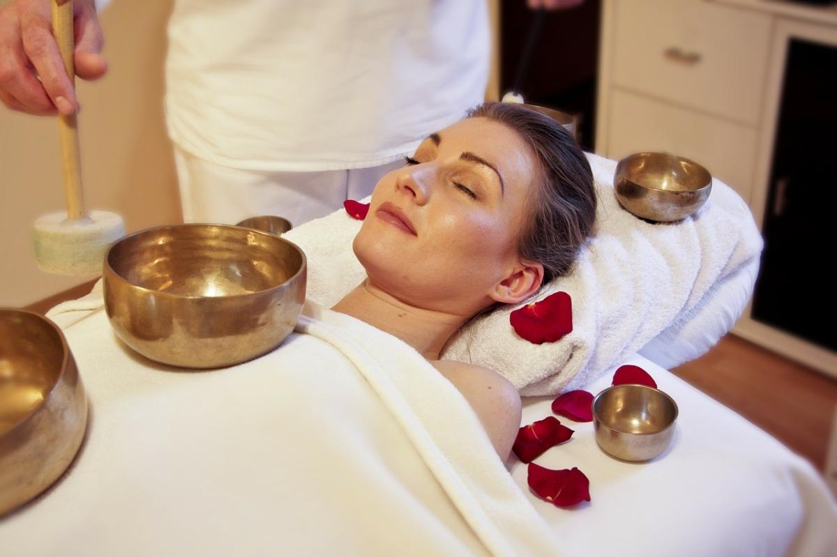 A woman rests on a massage bed with her eyes closed