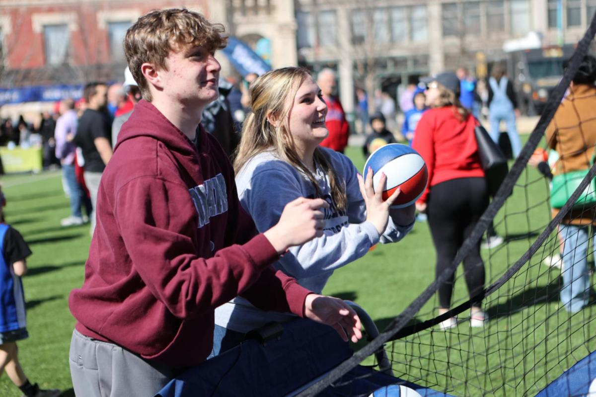 A teen girl and teen boy shoot hoops at Fan Fest in Naftzger Park