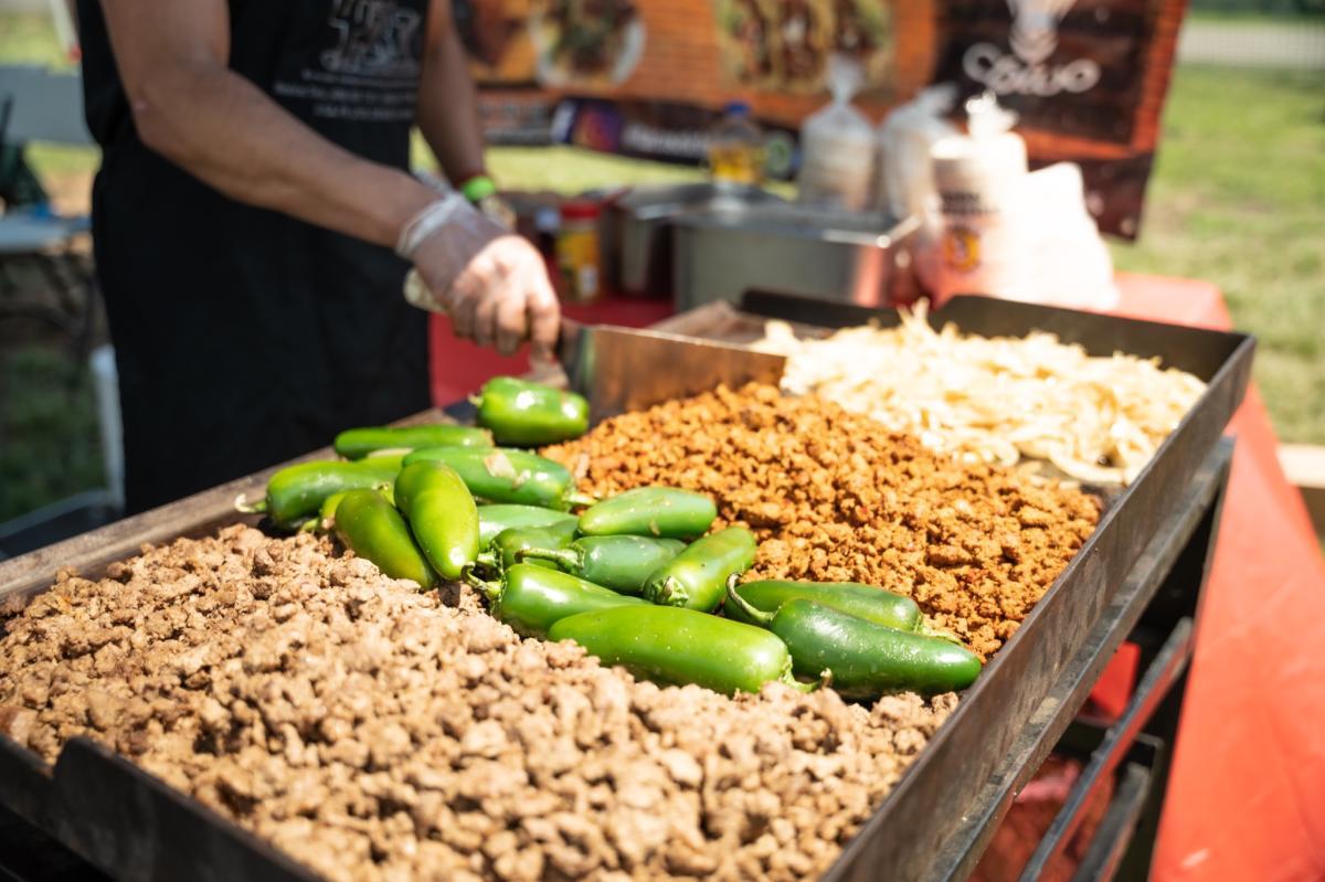 Hands are seen turning food on a grill at Wichita Taco Fest
