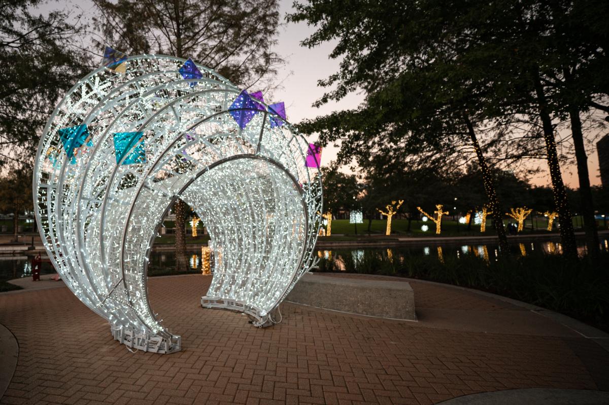 White and blue Christmas lights form an arch over a pathway along The Waterway.