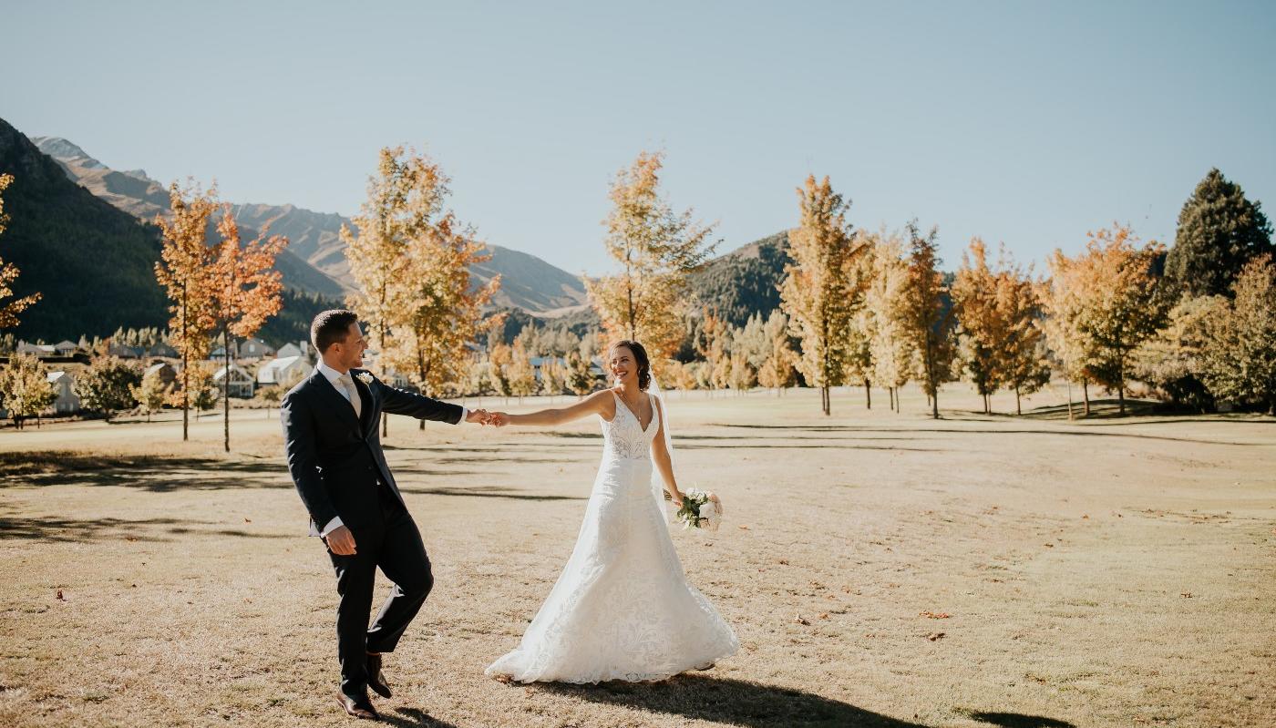 Married couple taking wedding photos in front of Autumn trees at Millbrook in Queenstown