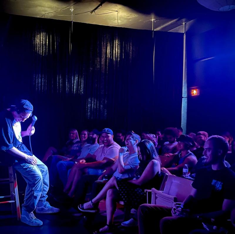 Audience members laugh at a comic on stage at Dry Heat Comedy Club