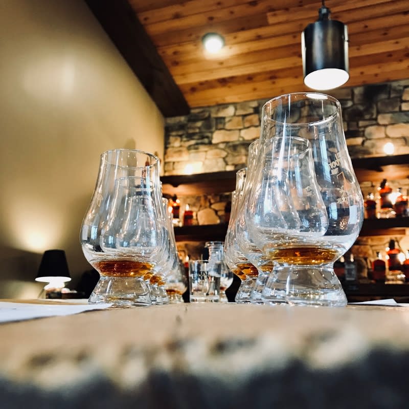 two rows of bourbon glasses holding a tasting flight of bourbon with a stone bar in the background