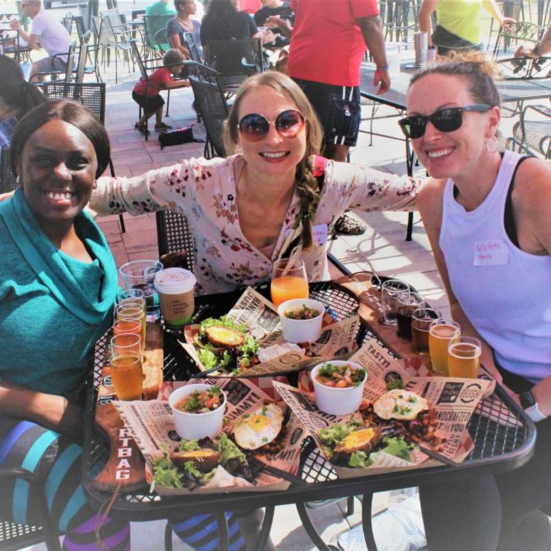 Three women enjoying lunch and drinks together on the outdoor patio at Dirtbag Ales in Cumberland County, North Carolina.