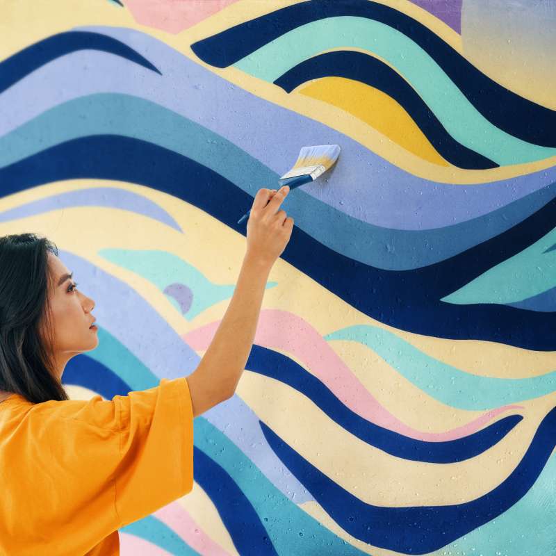 Muralist working on a mural with a paint brush