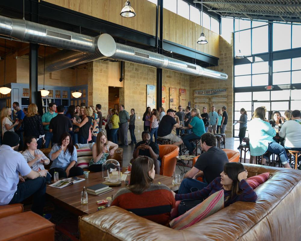 Large crowd of people sitting and standing throughout Deep Eddy Vodka's airy and bright tasting room.