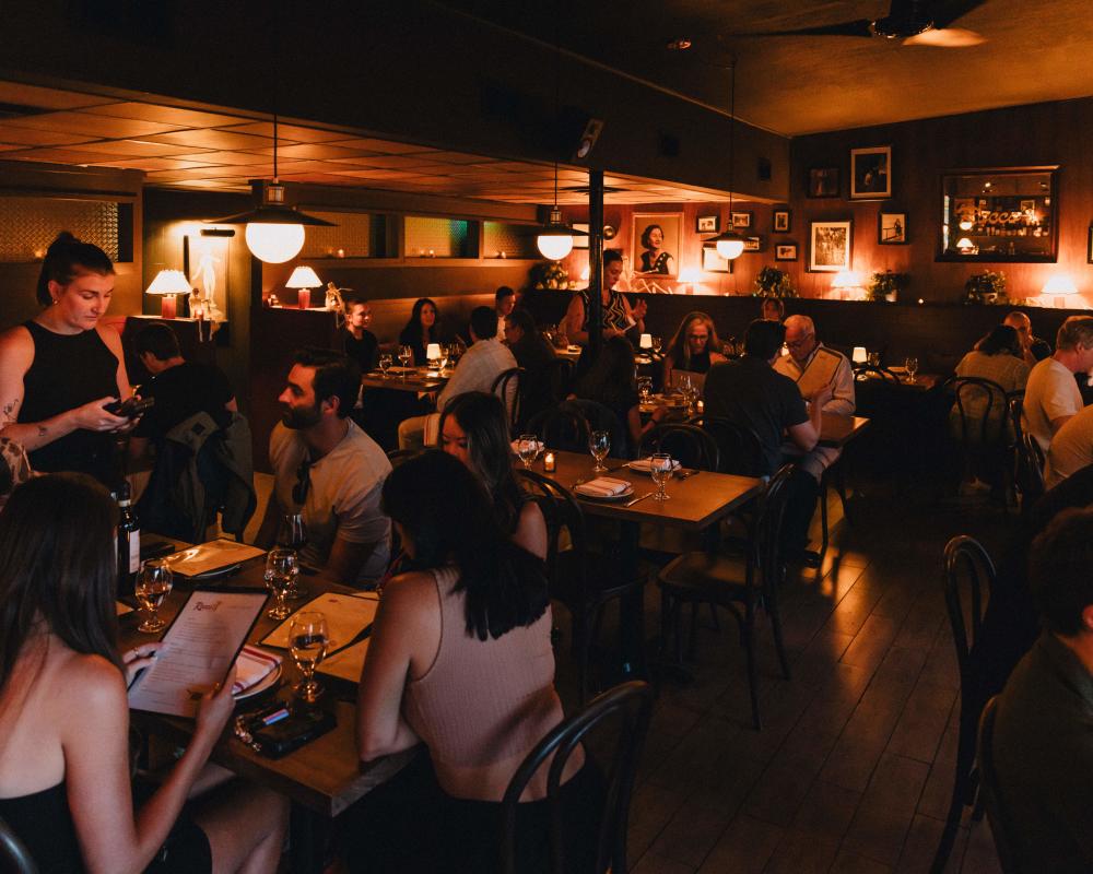 Image of the dark dining room at Rocco's with people sitting at tables eating.