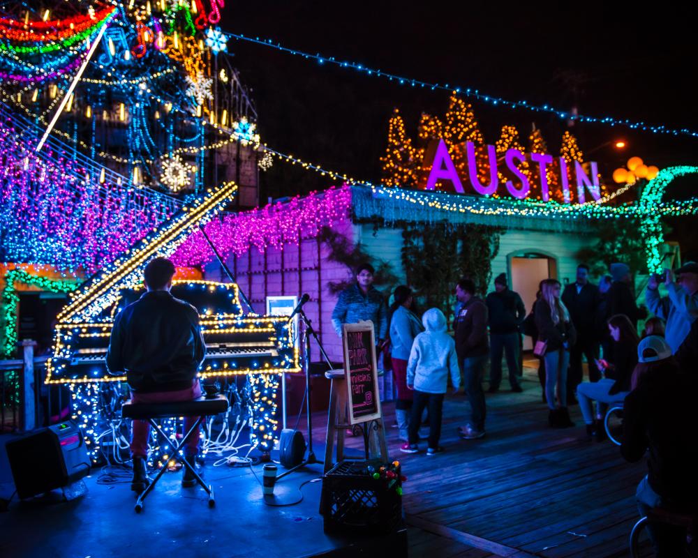 Man playing a piano outside at the Mozart's Christmas Light Show