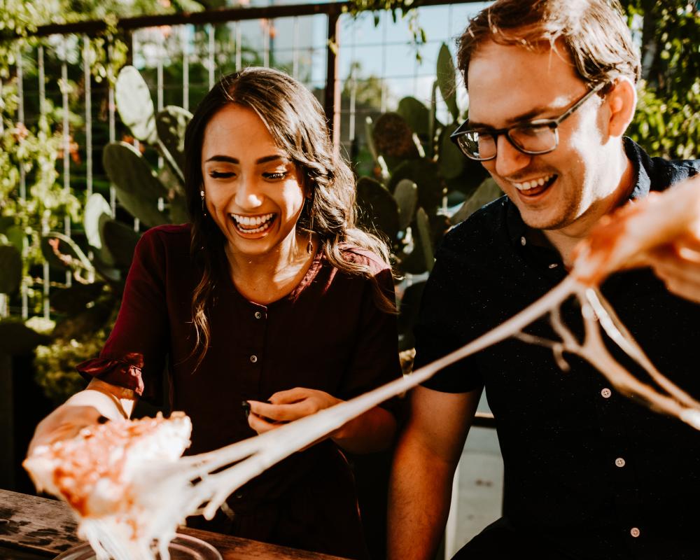 Couple pulling two pieces of cheesy pepperoni pizza apart from Via 313