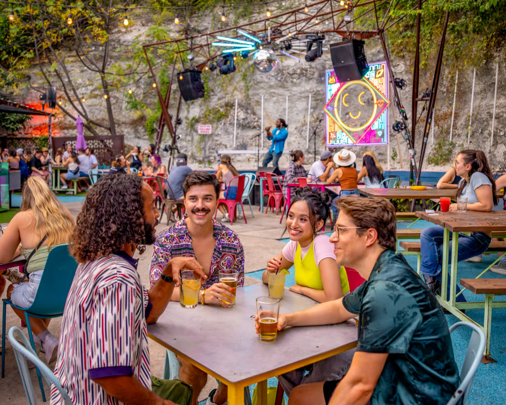 A group of men and women sitting at a table talking on the patio at Cheer Up Charlies.