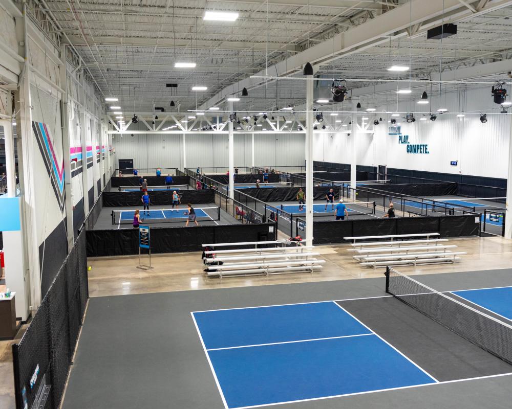 Interior of ACE Pickleball Club indoor pickleball facility, photo taken from a second-floor mezzanine above the pickleball courts