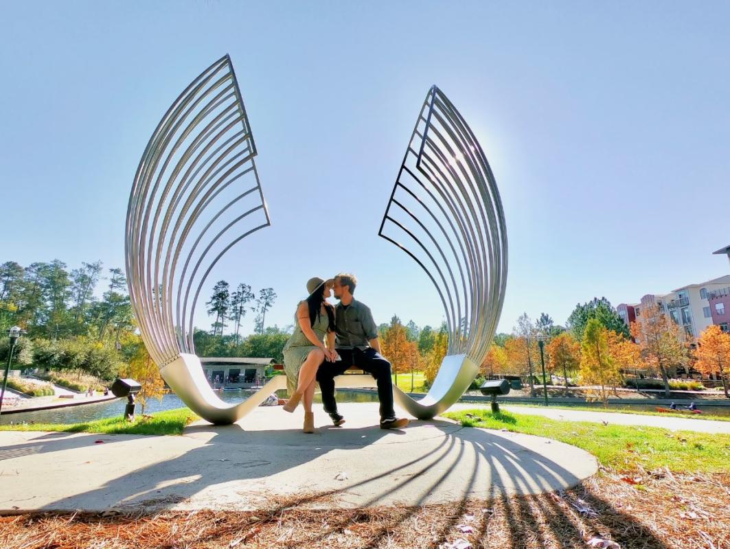 Couple sitting at an art bench with fall leaves in the background