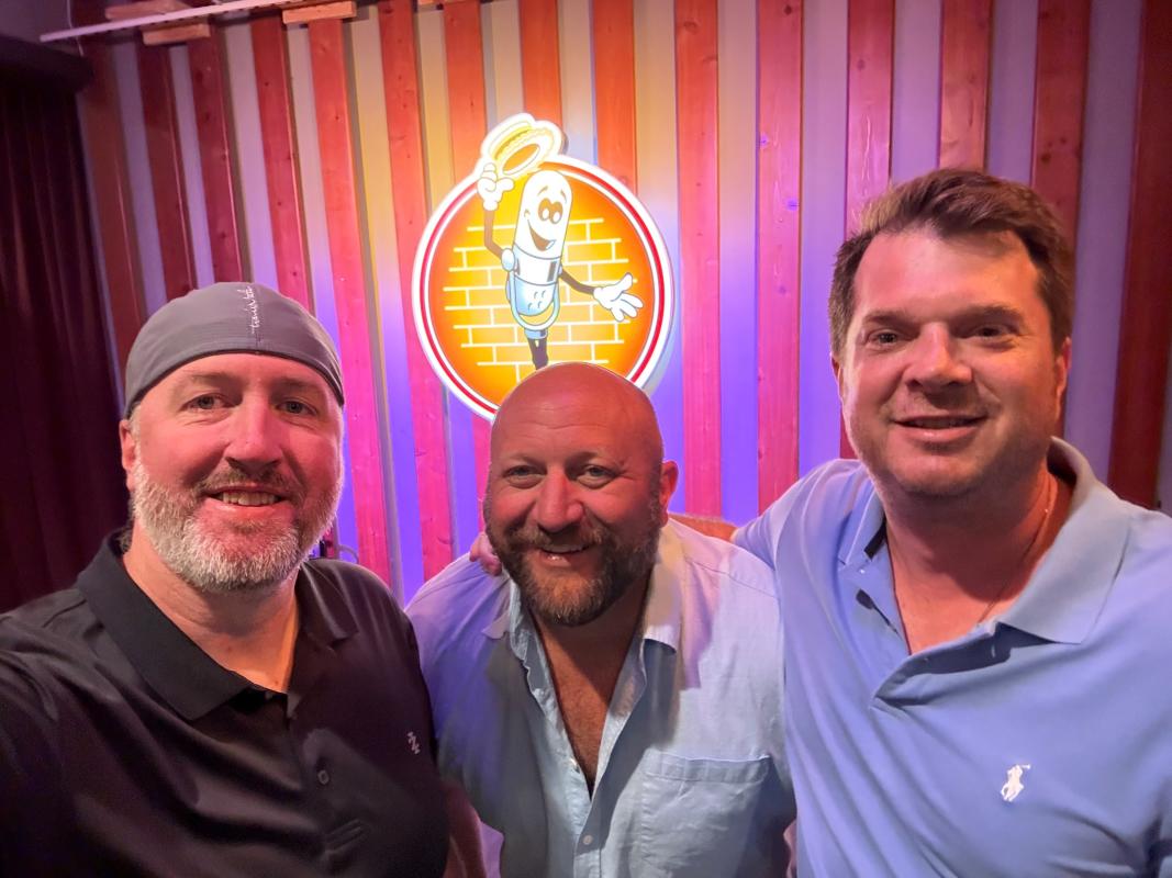Three friends take a selfie in front of the Funny Bone sign at the comedy club in St. Charles, Missouri.