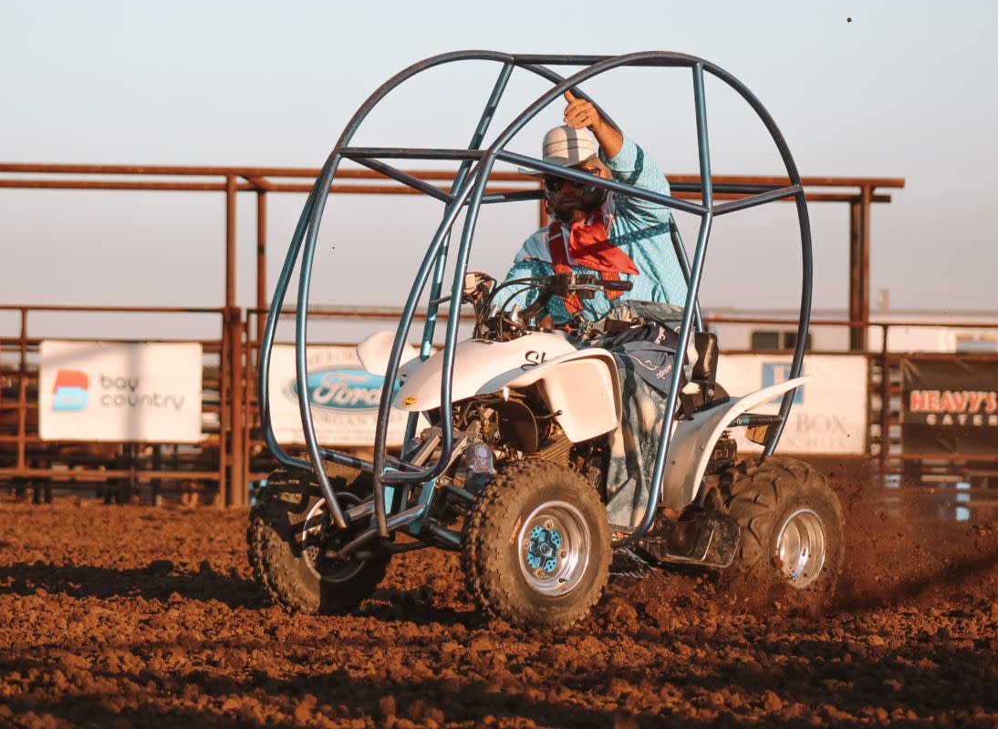 a man dressed in a collage of clothing and face painted like a clown sitting on a quad with a frame around it
