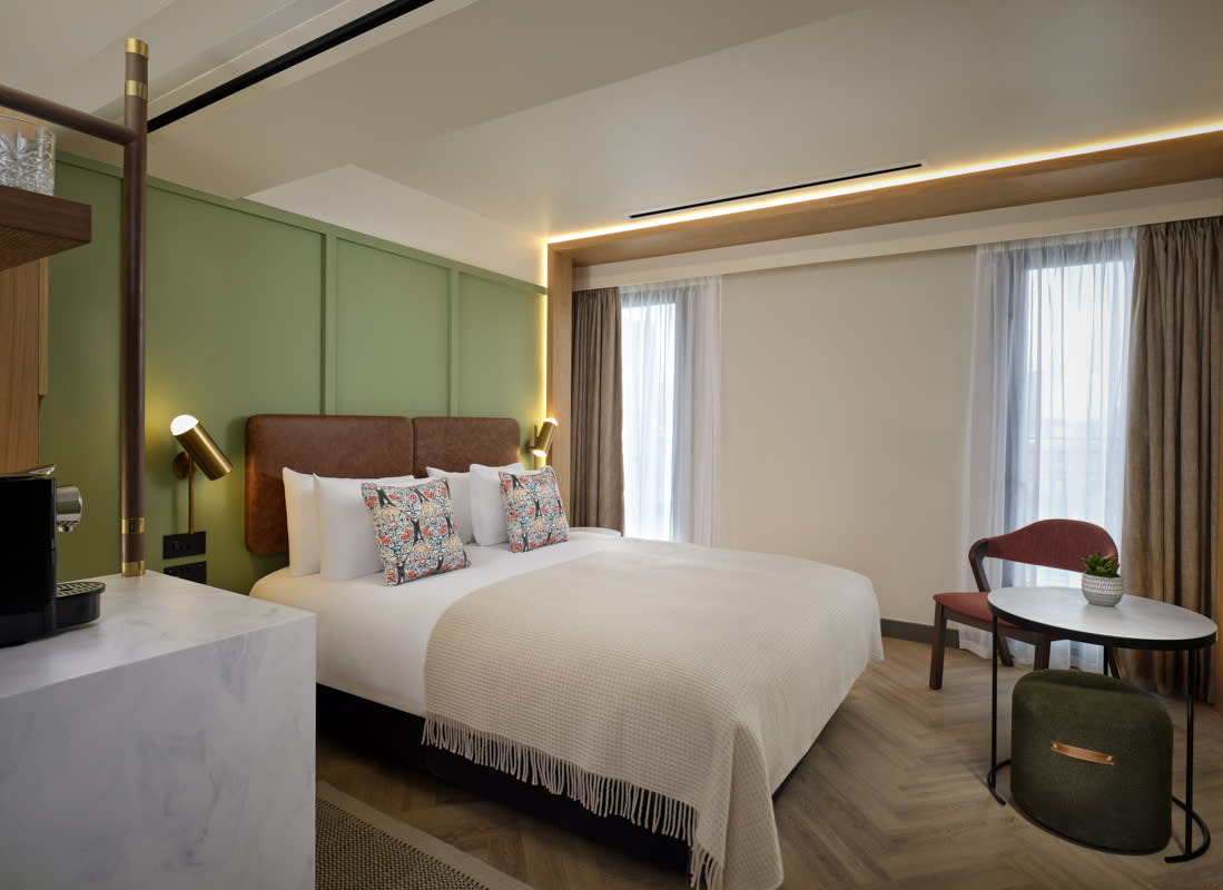 Hotel bedroom with green wall and desk with chair
