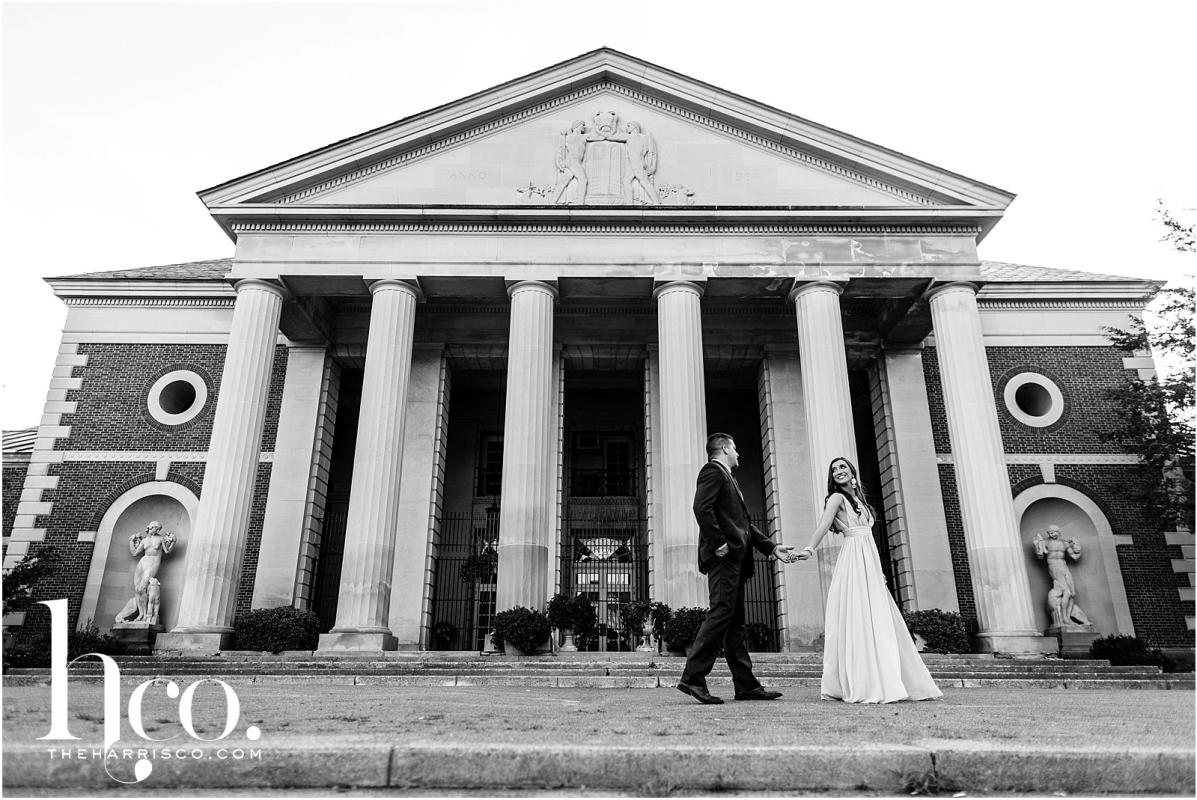Black and white shot of couple holding hands outside of Hall of Springs in Saratoga NY