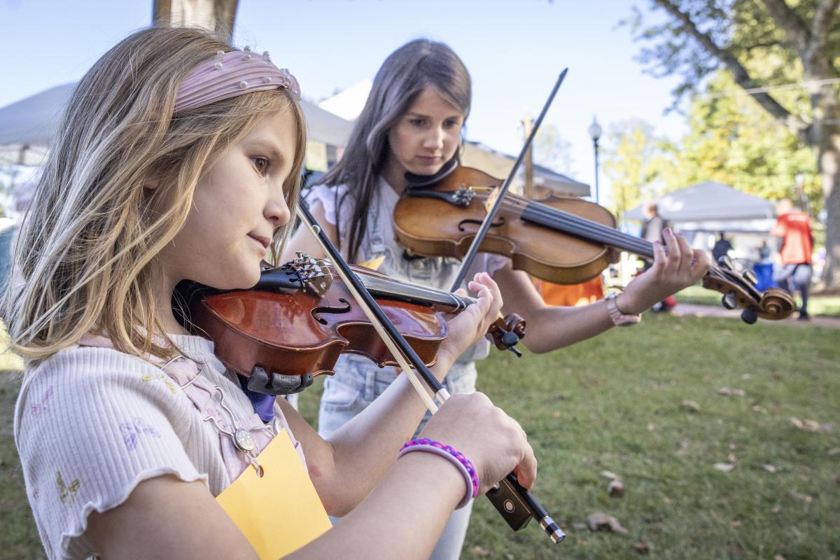 Two young girls play their fiddles at the Old Time Fiddlers Convention