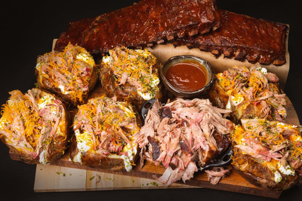 delicious spread of food from LawLers Barbecue including stuffed potatoes, ribs, and pork sandwiches with sauce