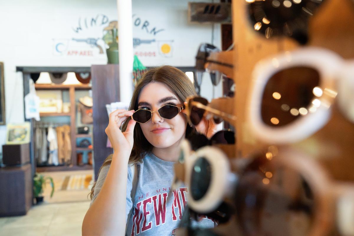 A college student tries on glasses at And Stuff Retail Collective.