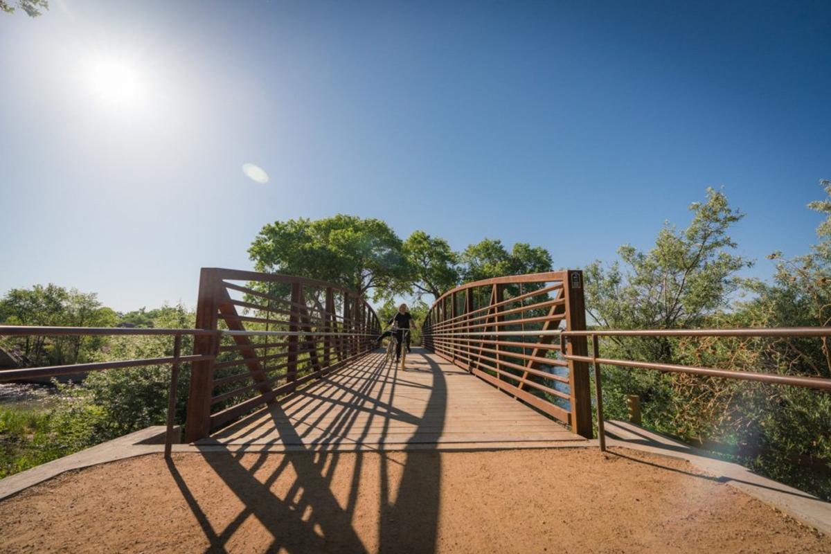 An individual cycling over the Paseo de Bosque Bridge.