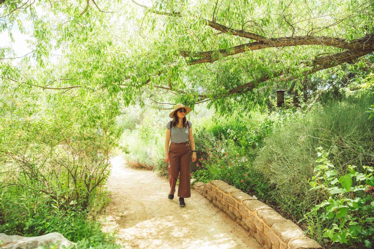 A woman walking along a path at the ABQ BioPark Botanic Garden