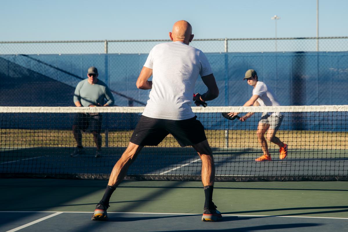 Three people play a game of pickleball
