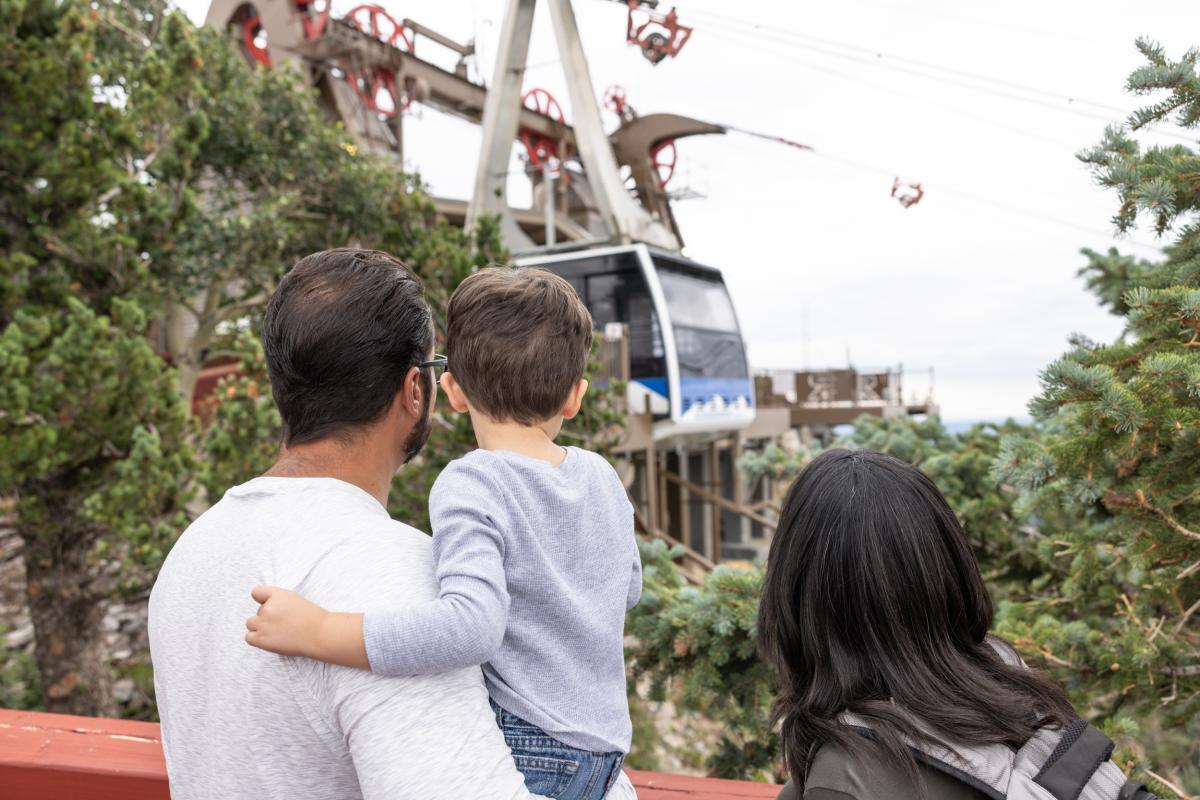 A family watches a Sandia Peak Aerial Tramway tram car