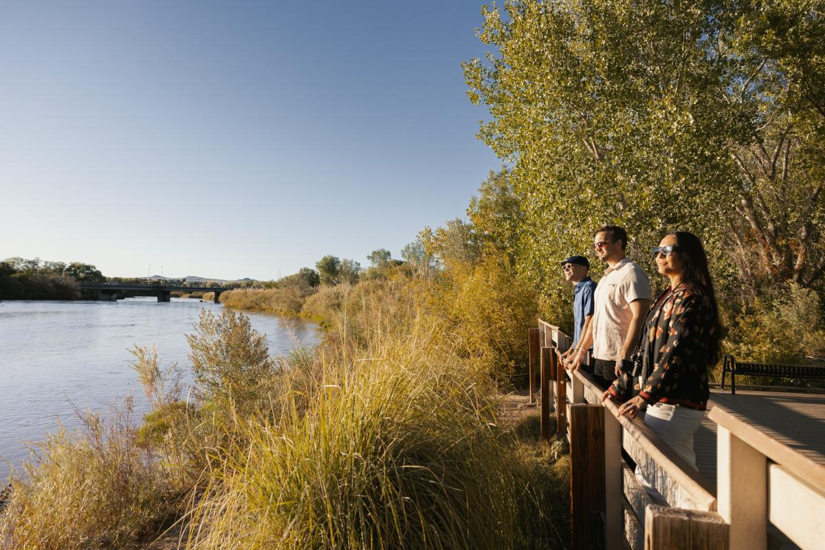 Three people look out over the Rio Grande in the bosque.