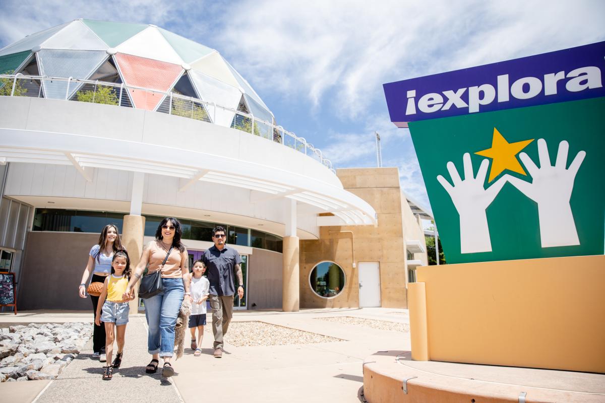 A family walks by the Explora sign in front of the museum