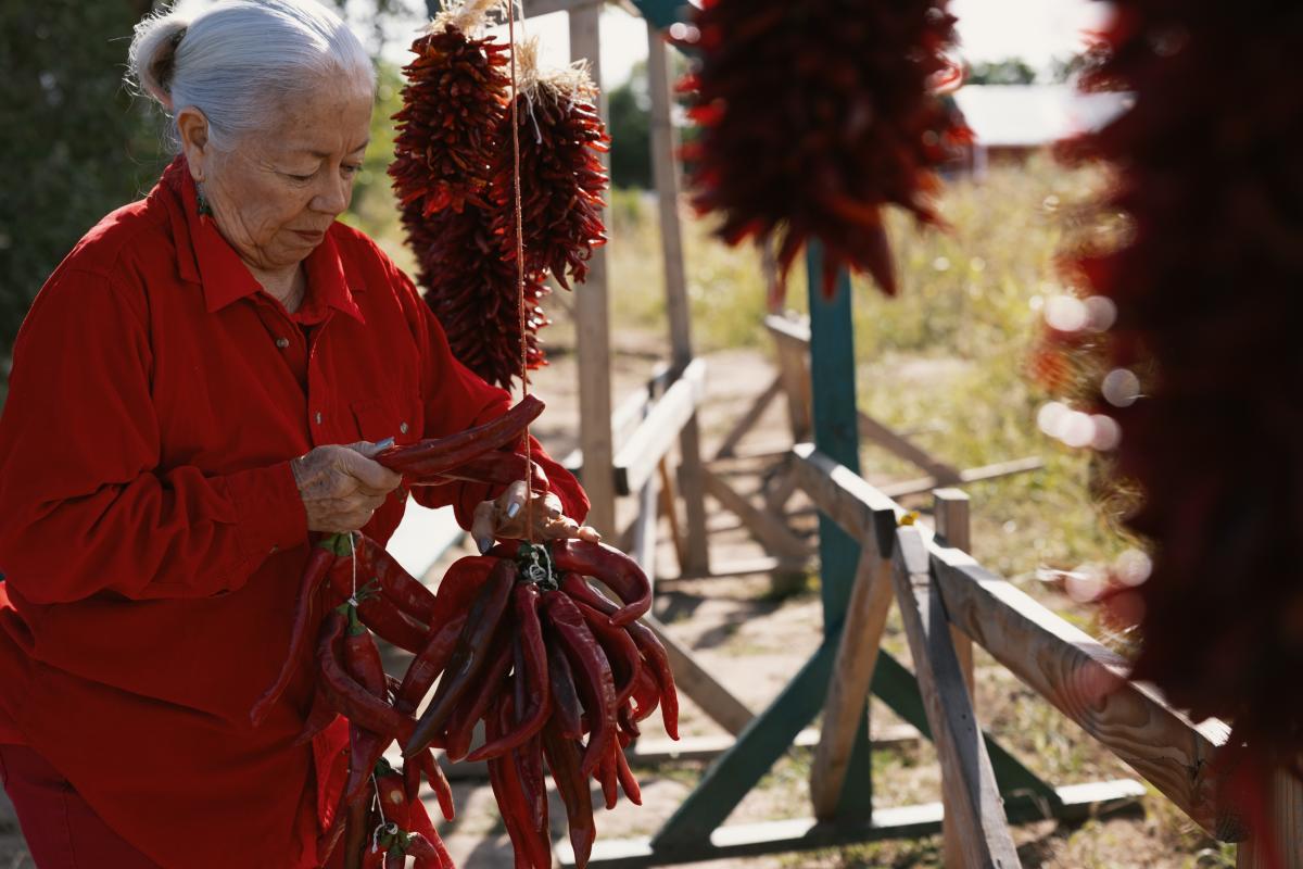 A woman assembles a red chile ristra at Big Jim Farms