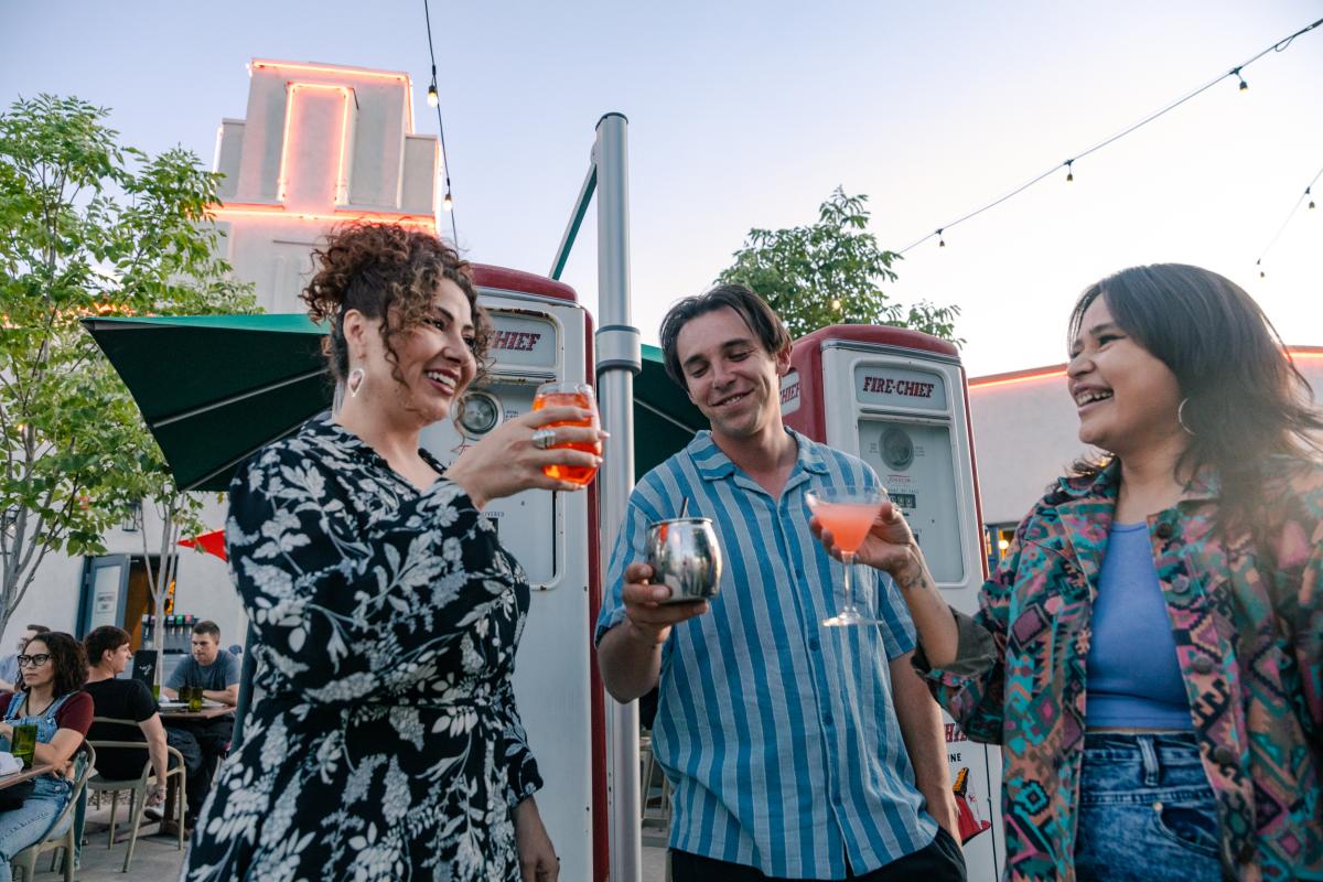 Two women and a man hold drinks at M'Tucci's Bar Roma