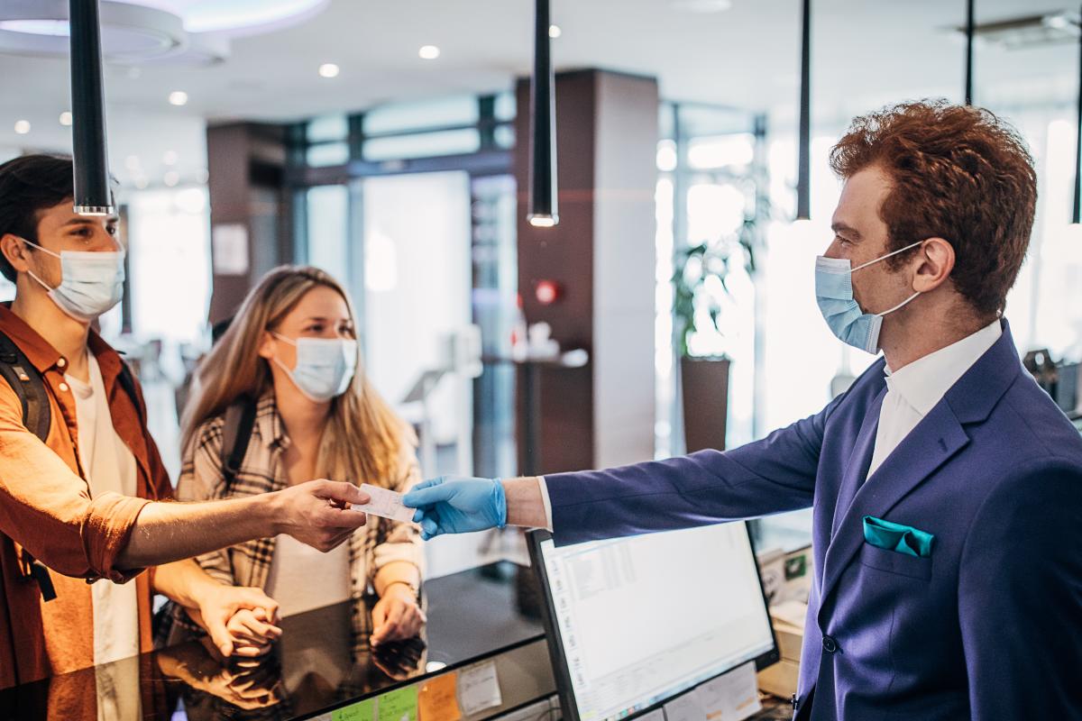 Man and women checking into hotel with face masks on