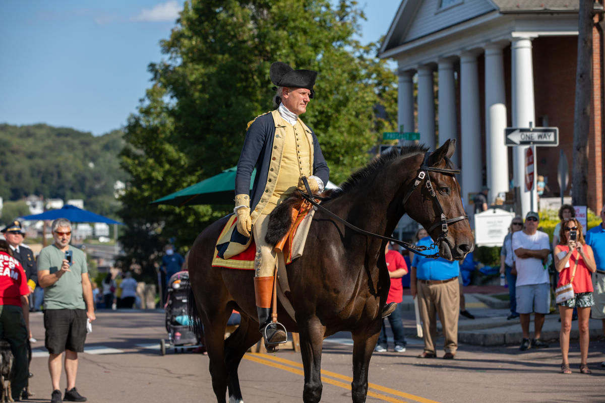 George Washington reenactor rides horse down historic street during Heritage Days Festival in Cumberland, Maryland.
