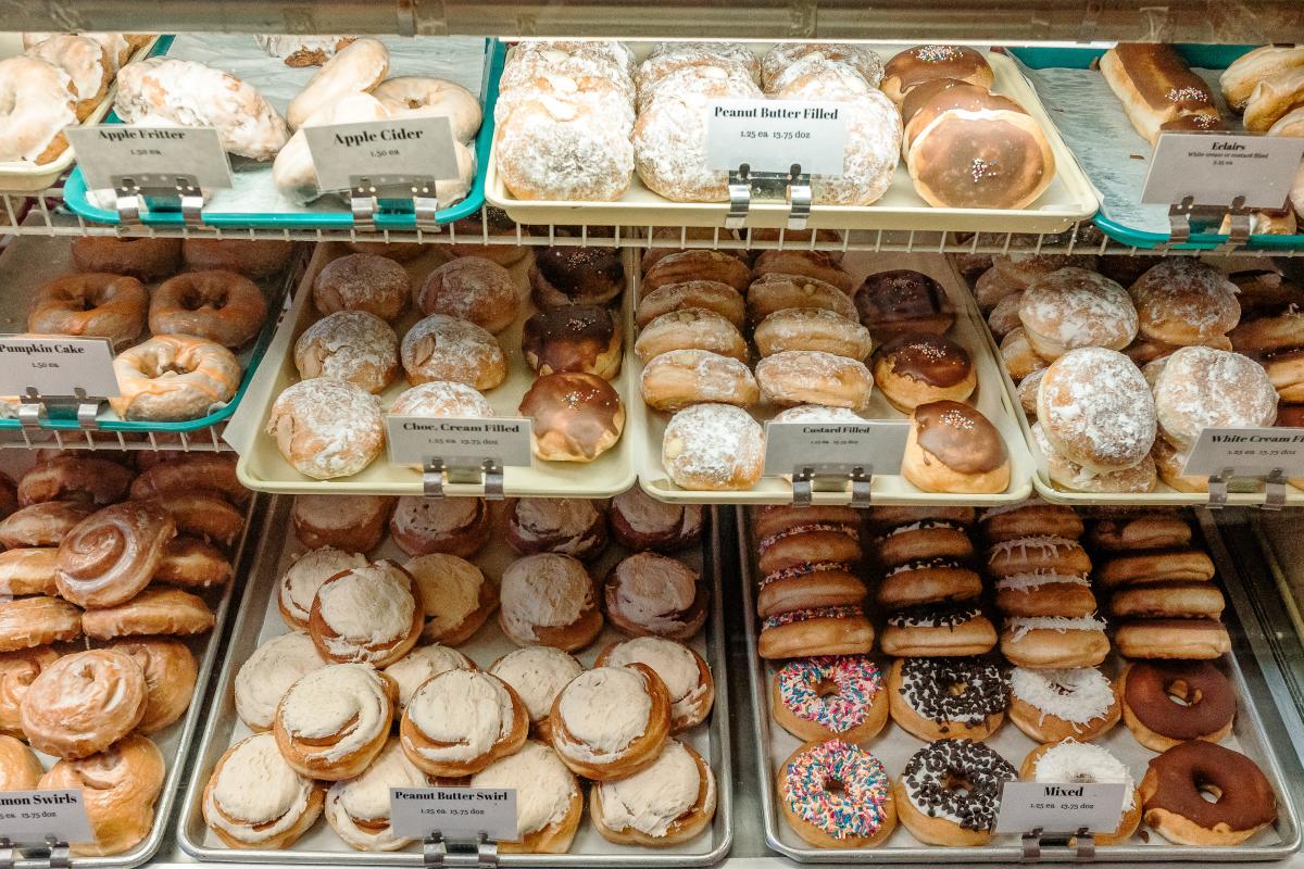 A variety of donuts on tray in a display window at Lorenzo's Bakery.