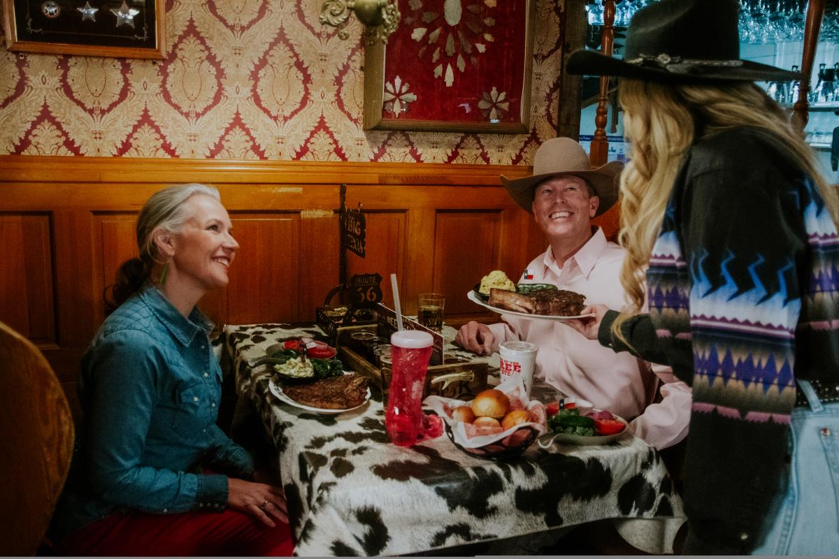 Couple getting served steaks by a waitress at The Big Texan