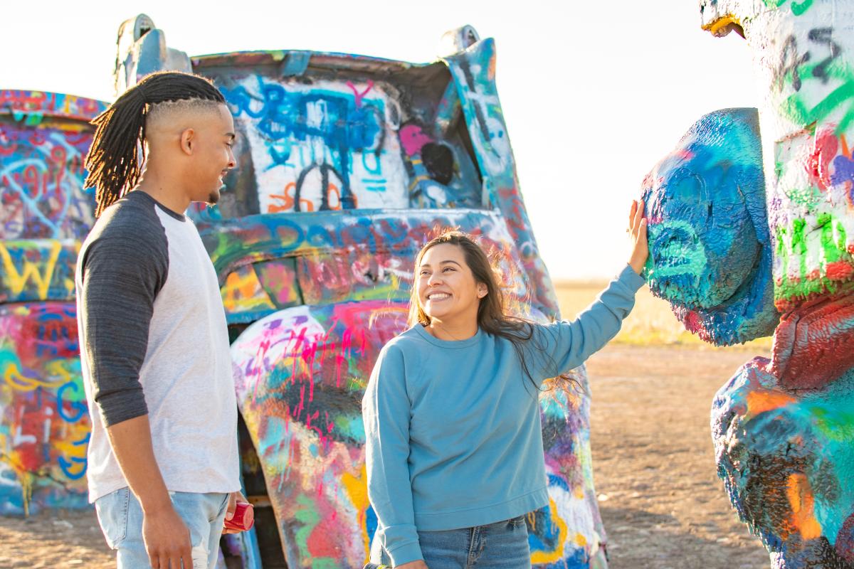 A couple posing in front of the Cadillacs at Cadillac Ranch in Amairllo, Texas