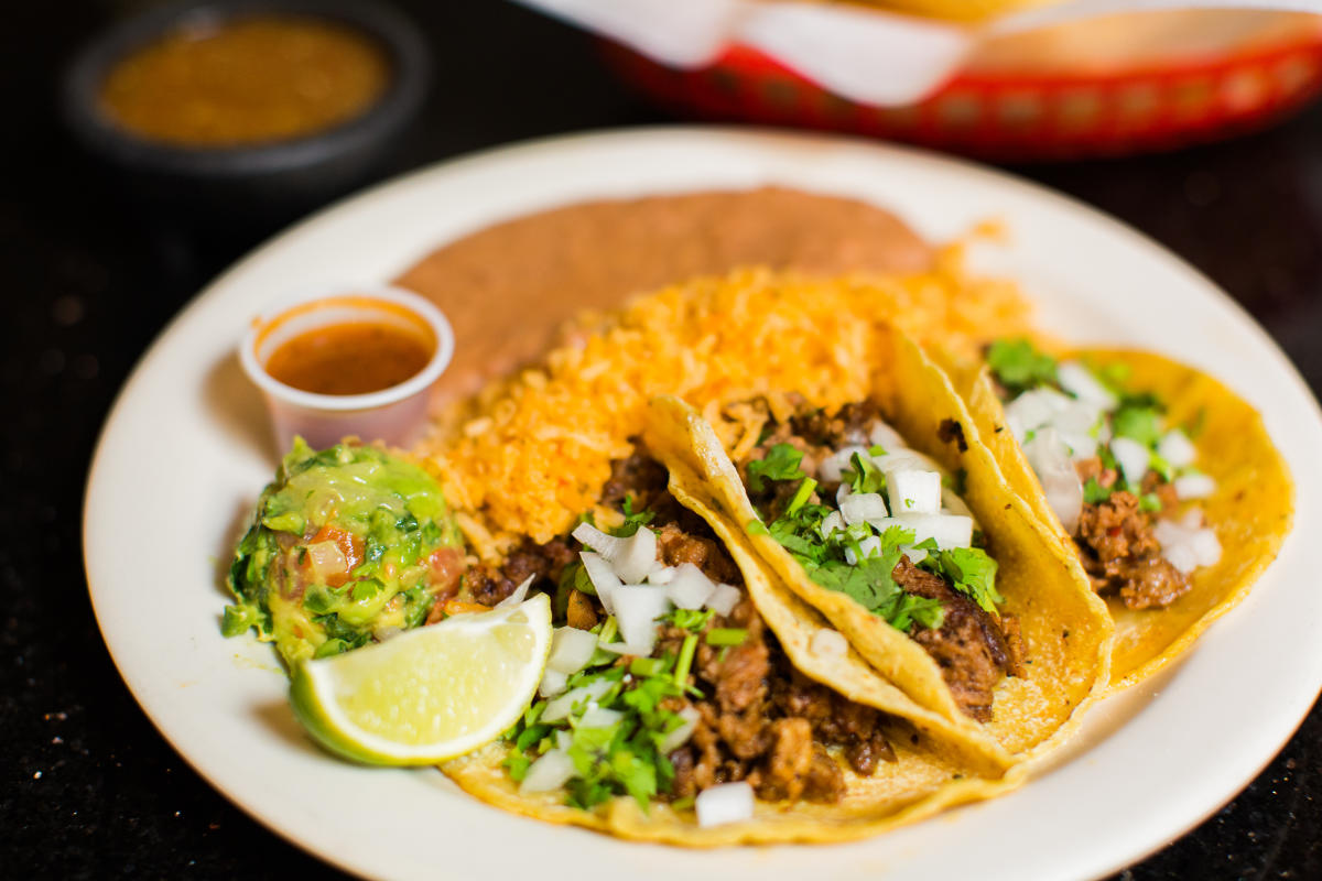 Plate of 3 al pastor tacos, rice, beans, a lime, salsa, and scoop of chunky guacamole from El Tejavan in Amarillo, Texas