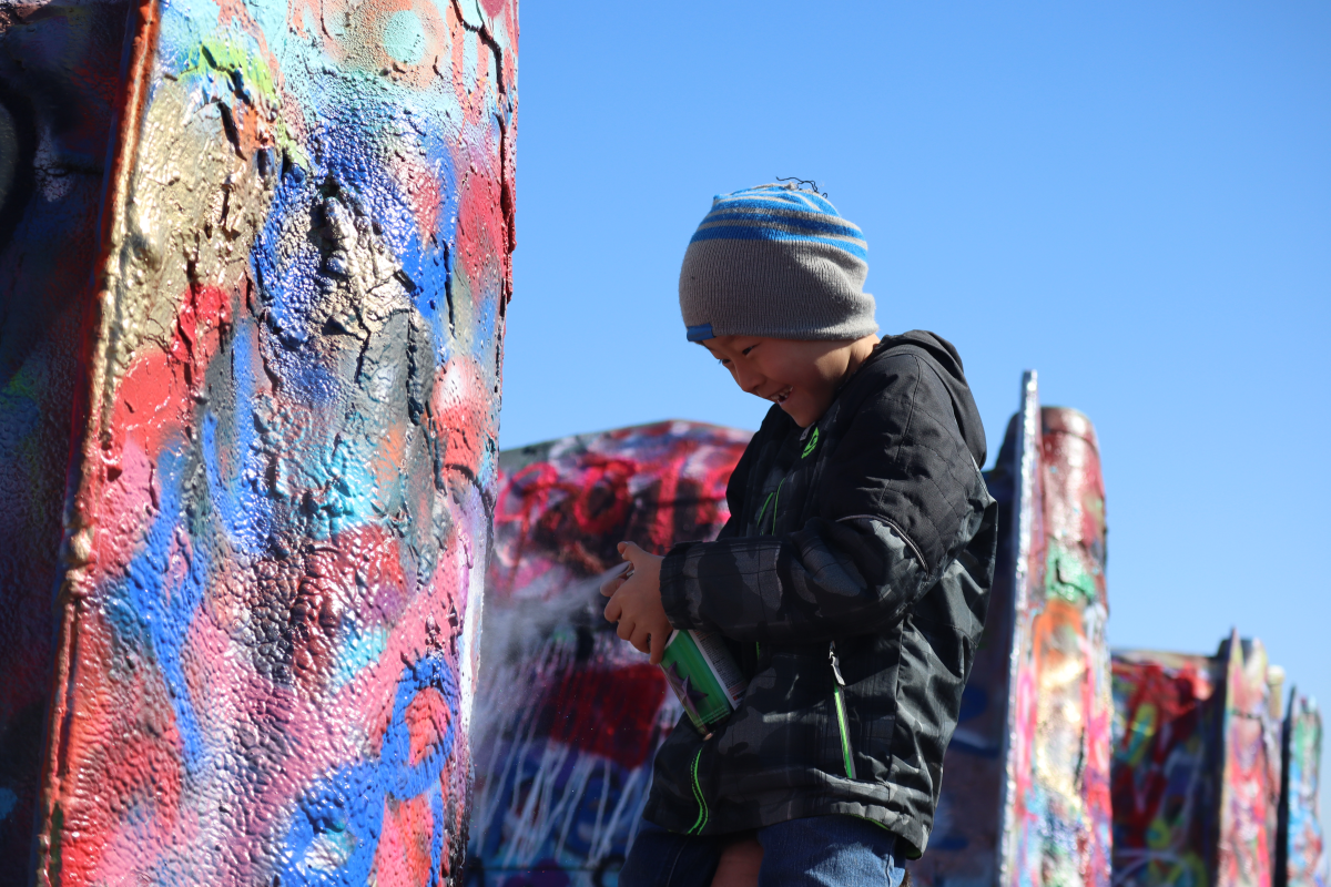 kid spray painting car at cadillac ranch