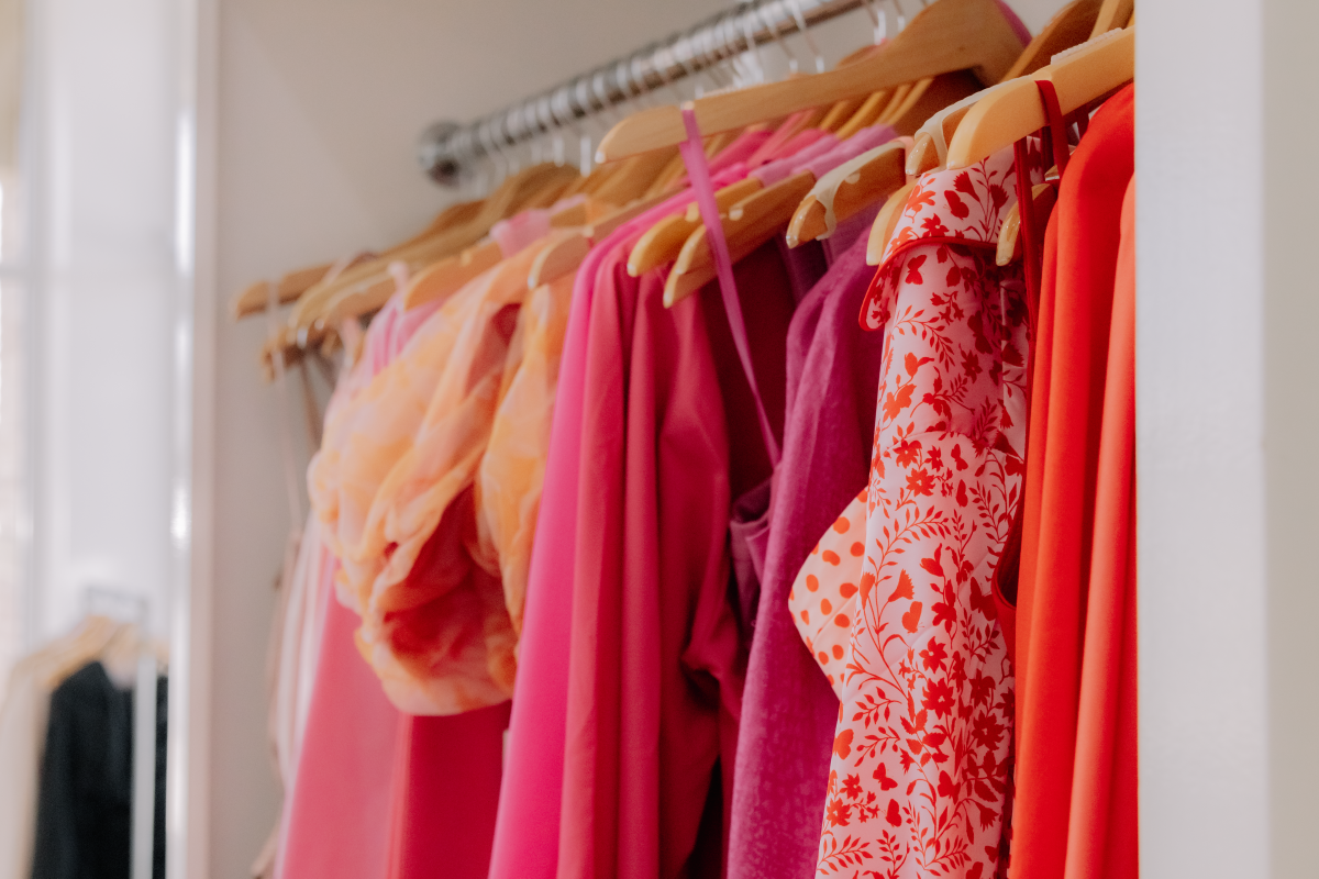 Clothing rack full of silky blouses, pink sweaters, and white tops