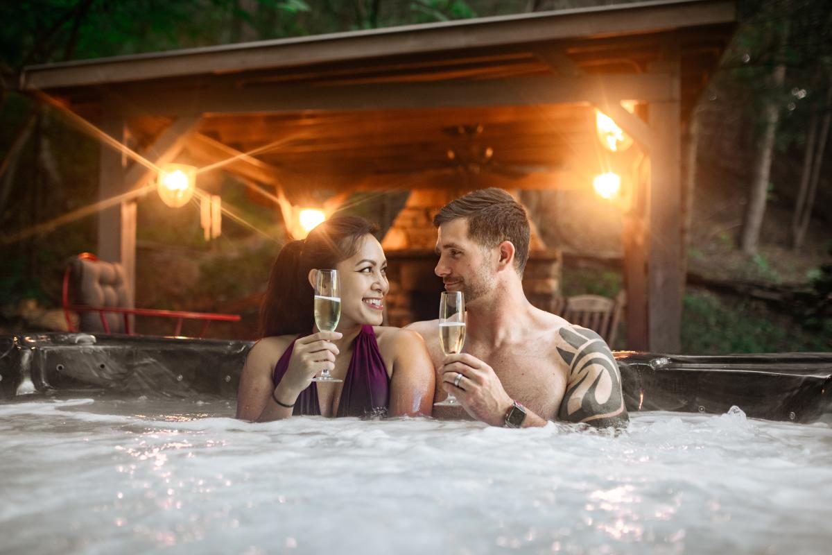 Couple sitting in a hot tub drinking Champagne.