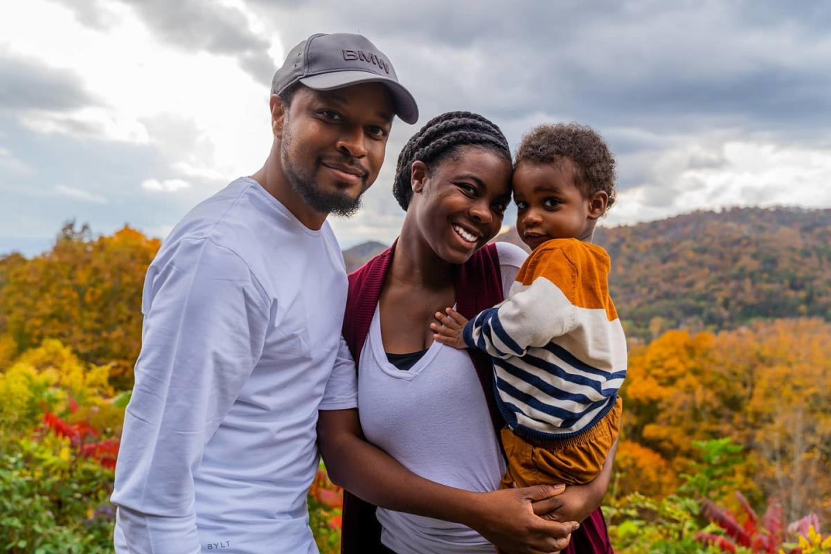Mother holding son with father next to them in front of fall mountain backdrop