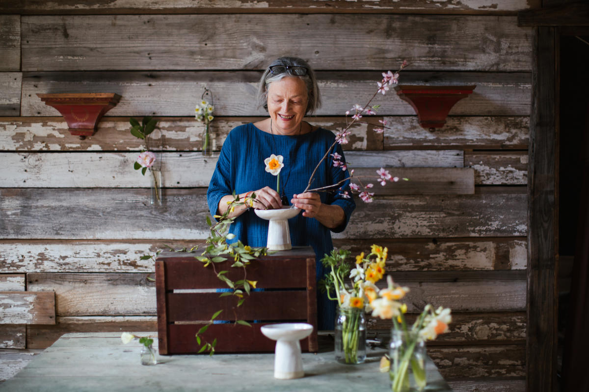 Rebecca Wood, founder of R. Wood Studio, arranges flowers in a white vase. Rebecca draws her inspiration from the South's natural beauty.