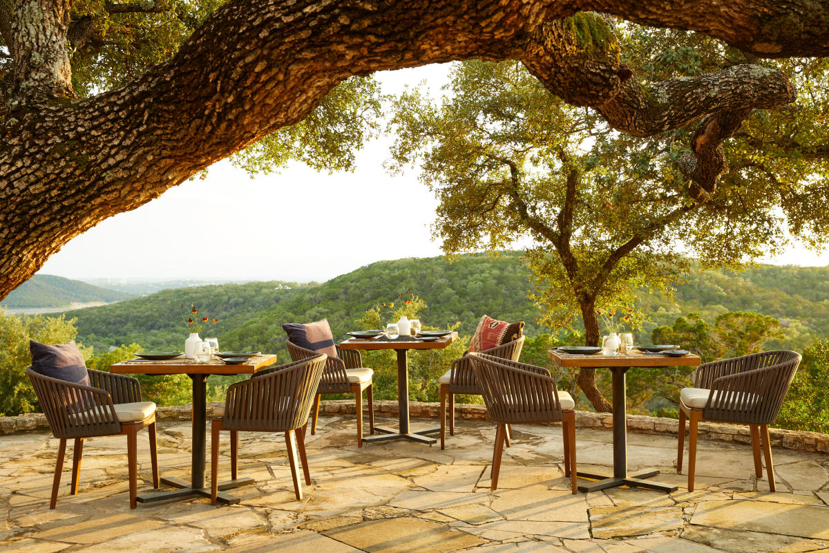 Image of the outdoor patio with tables overlooking the green rolling hills of the Texas Hill Country.