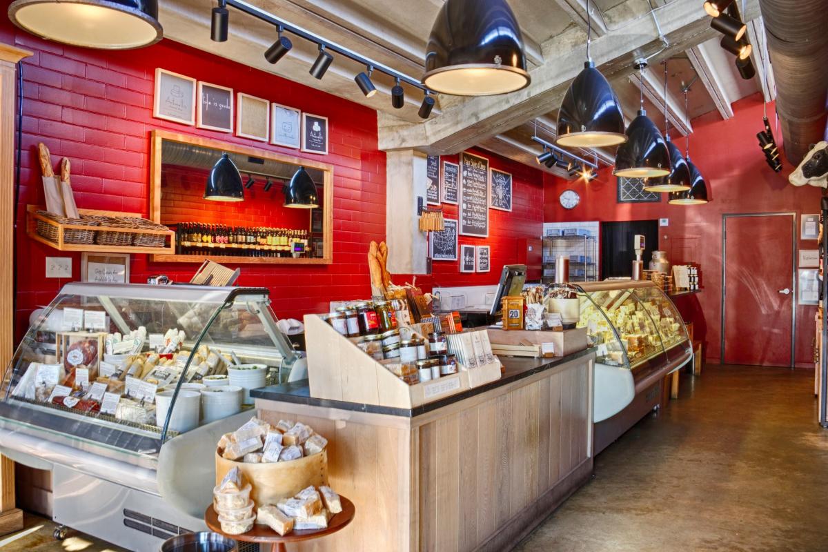 The Antonelli's Cheese Shop with bright red walls and large glass cases displaying available cheeses for purchase.