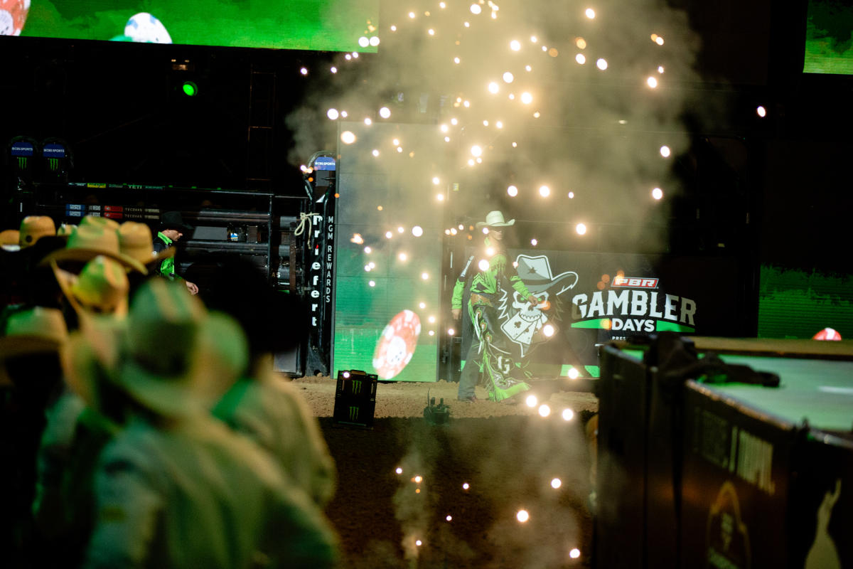 Fans in cowboy hats watching the Austin Gamblers team walk into the ring with fireworks and smoke clouding the image.